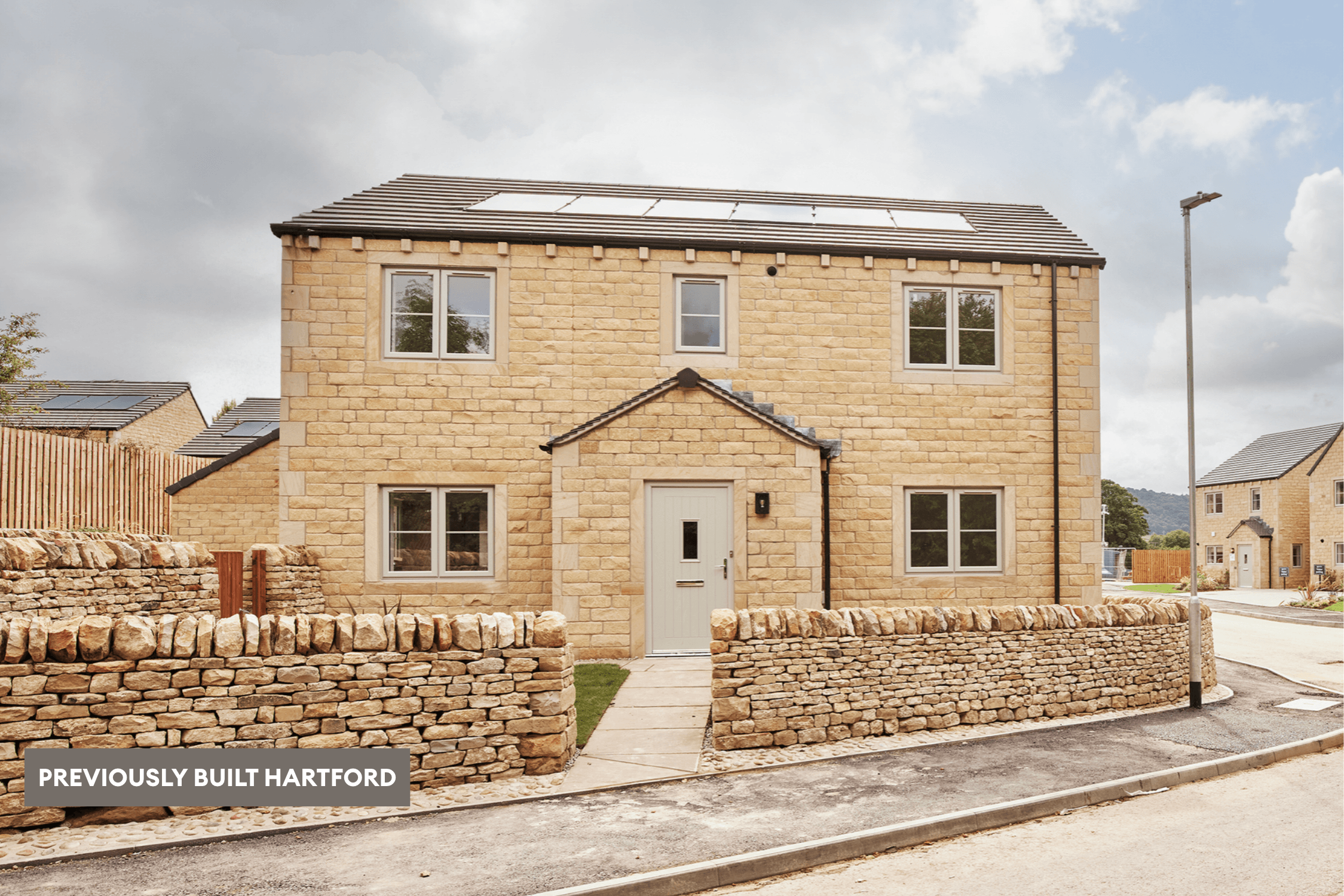 Previously built Hartford home in natural stone, with solar panels, a pale front door and traditional dry-stone boundary walls within a completed residential development.